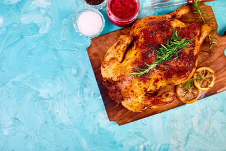 Baked whole chicken with sauces on wooden board on blue background. Christmas chicken. Dinner. Appetizerの写真素材
