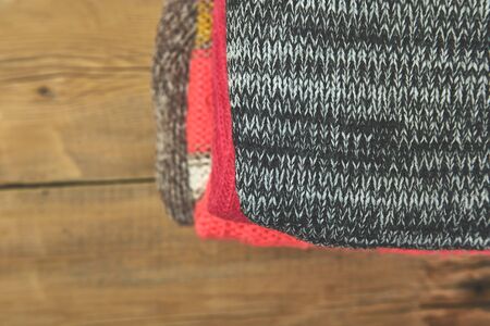 Stack of cozy knitted sweaters. A pile of warm sweaters on a wooden table on rustic background. Autumn and winter clothes. Copy space. Flat layの写真素材