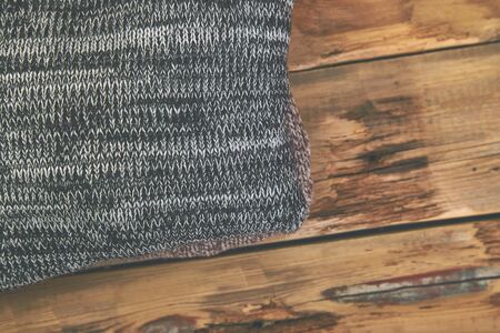Stack of cozy knitted sweaters. A pile of warm sweaters on a wooden table on rustic background. Autumn and winter clothes. Copy space. Flat layの写真素材