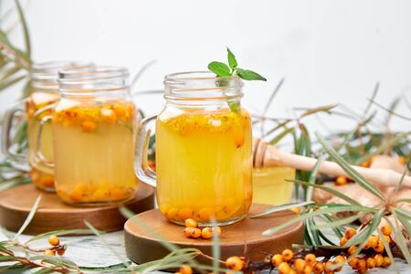 Hot sea buckthorn tea with ginger and honey and sea buckthorn berries on white table. Top view. Vitaminic healthy.の写真素材