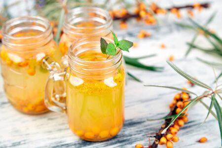 Hot sea buckthorn tea with ginger and honey and sea buckthorn berries on white table. Top view. Vitaminic healthy.の写真素材