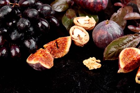Autumn harvest frame background. Autumn food still life with season fruits grape and figs, honey on a black table. Thanksgiving day.の写真素材