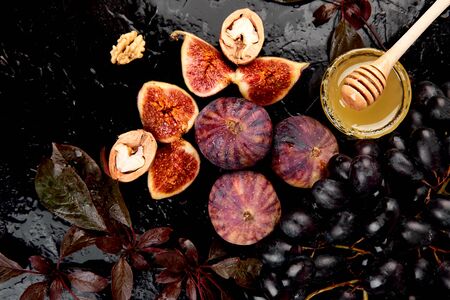 Autumn frame background. Autumn food still life with season fruits grape and figs, honey on a black table. Thanksgiving day.の写真素材