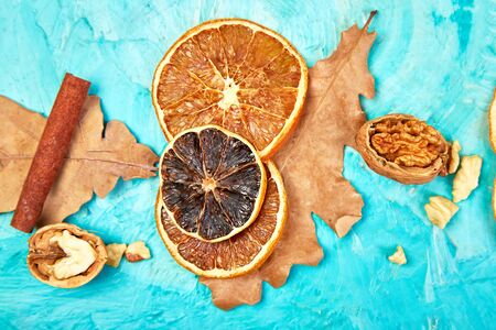 Autumn composition background with slices of dried oranges, leaves and cinnamon on a blue background, autumn concept, flat lay, top viewの写真素材
