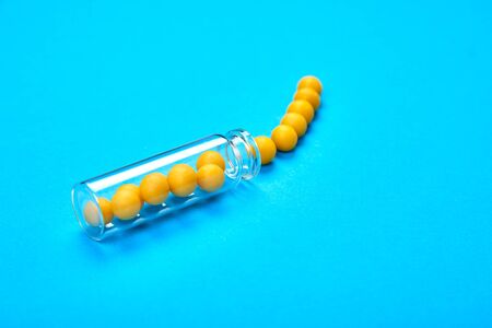 Minimalism style template for medical blog. Small glass bottle fwith small yellow pills spilled out blue background. Pharmaceutical concept. Medicine pills. Flat layの写真素材