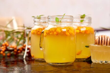 Vitaminic healthy sea buckthorn tea in small glass cups with fresh raw sea buckthorn berries, honey on black backgroundの写真素材