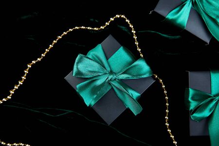 Luxury black gift boxes with green ribbon on shine velvet background. Christmas, birthday party...