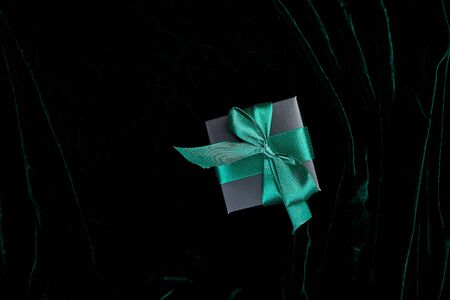 One luxury black gift boxe with green ribbon on shine velvet background. Christmas, birthday party presents. Father Day. Flat lay. Copy space. Top view.の写真素材