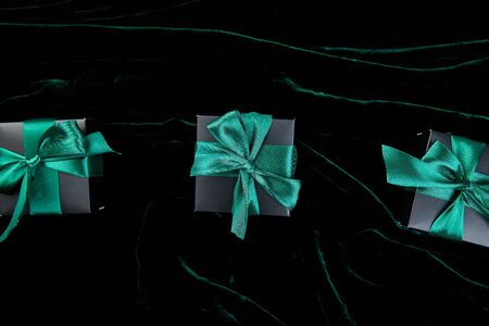 Luxury black gift boxes with green ribbon on shine velvet background. Christmas, birthday party...