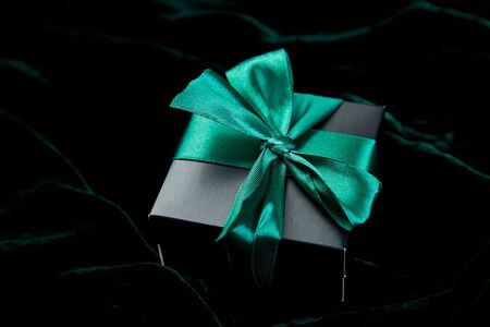 One luxury black gift boxe with green ribbon on shine velvet background. Christmas, birthday party presents. Father Day. Flat lay. Copy space. Top view.の写真素材