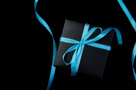 One luxury black gift boxes with blue ribbon on shine black background. Flat lay. Copy space. Top view.の写真素材