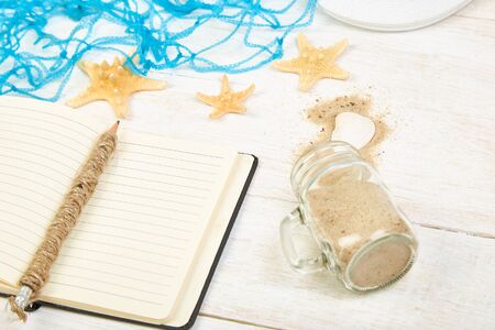 Notebook, starfishes and seashells, glass with sandの写真素材