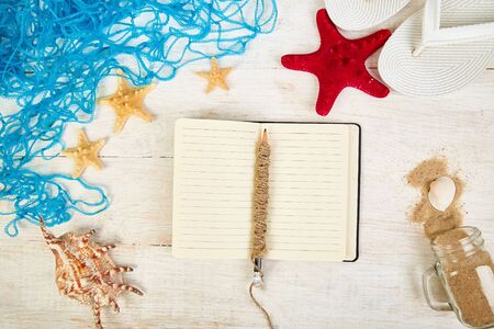 Notebook, starfishes and seashells, glass with sand
