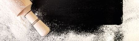 Copy space around rolling pin, flour and egg on black background. Top view. Frame. Ingredients and...