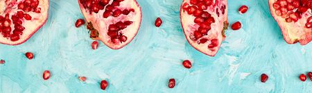 Banner with Half pomegranate fruit on blue background. Fresh red ripe pomegranate and seeds Free space for text . Overhead. Top viewの写真素材