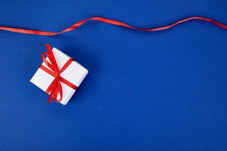 Luxury white gift boxes with red ribbon on blue trend color background. Valentine Day, Christmas, birthday party presents. Mother or Woman Day. Flat lay. Copy space. Top view.の写真素材