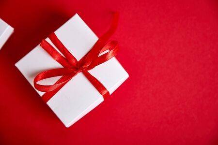Luxury white gift boxes with red ribbon on red background. Valentine Day, Christmas, birthday party presents. Mother or Woman Day. Flat lay. Copy space. Top view.の写真素材