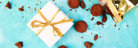 Banner of Chocolate Candy truffles fall out golden luxury box ad gift on blue background. Copy space, Dessert. Cocoa candies. delicious. tasty. Flat layの写真素材