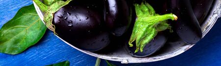 Banner of Fresh eggplant in grey basket on blue wooden table.の写真素材