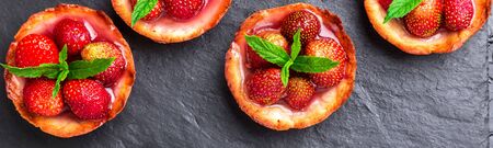 Banner of Homemade strawberries tarts on slate plate, black background. Top view.の写真素材