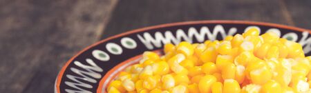 Banner of Canned corn in a brown bowl on wooden background. Copy space.の写真素材
