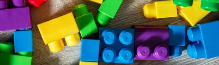 Banner of Bright plastic construction blocks on grey wooden background. Developing toys. Early learning. Frame. Top view.の写真素材