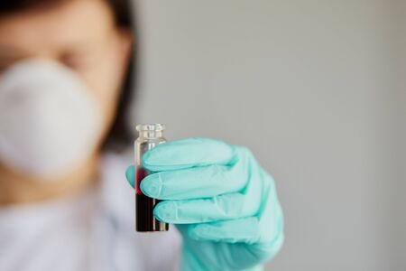 Young woman holding test tubes with blood and antidote in her hand. Coronavirus blood Test tube....