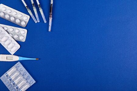 Coronavirus epidemic, pharmacy flat lay on a blue background with pills, syringe, thermomete. Medicine and healthy concept.の写真素材