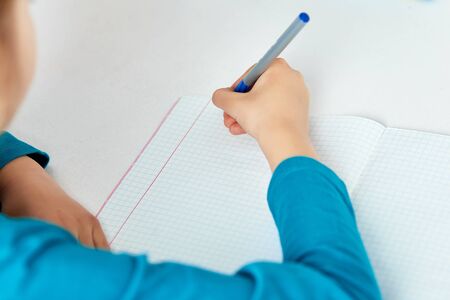 Schoolgirl doing homework, writing, studying lesson, coronavirus home school, social distance during quarantine,  online education concept, home schooler. Stay at home, stay safe.の写真素材