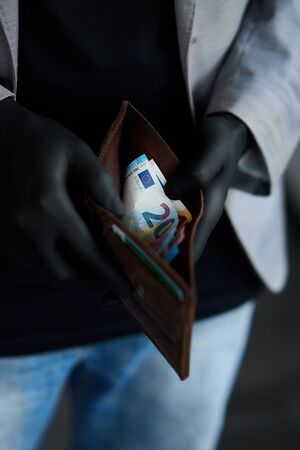 Man holding a wallet with money euro in hand in black medical gloves.の写真素材