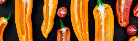 Banner of Mixed of half red and yellow pepper with a green branch near cherry tomato on a black...