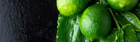 Banner of Wet spinach and lime on black background. Green fruit. Detox. Fresh. Copy space. Top view