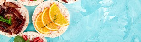 Banner of Snack with rice crispbread and fresh fruits on blue background. Healthy food concept. Flat lay, top view, round. Healthy snack with crisp bread. Easy appetizer recipe.の写真素材