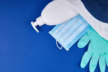 Protective medical mask, sanitizer gel and gloves in white bag on blue background. Protective...
