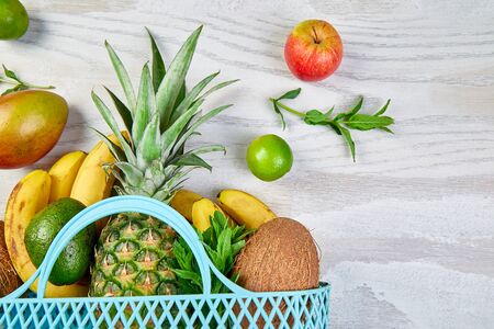 Grocery shopping bag with organic exotic fruits on white background. Flat lay of variety of fresh...