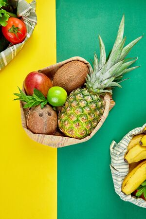 Eco shopping bags with organic fruits and vegetable on yellow green background. Flat lay, top view. Zero waste, plastic free lifestyle concept. Healthy veggie food diet and detox.の写真素材