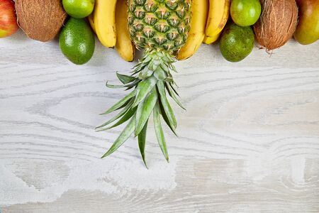 Flat lay of exotic fruits on white background - mango, pineapple, banana, avocado, coconut, lime. Top view. Creative layout made of tropical fruits, copy space, summer concept.の写真素材