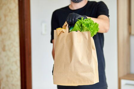 Courier man in black delivery box with food, contactless delivery. Service quarantine pandemic...