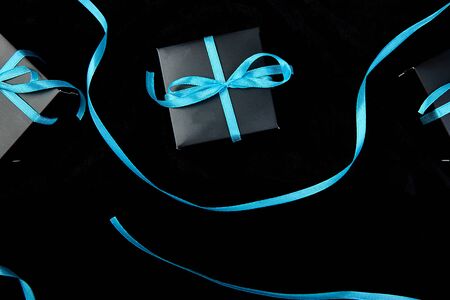 Luxury black gift boxes with blue ribbon on shine black background. Christmas, birthday party presents. Father Day. Flat lay. Copy space. Top view.の写真素材