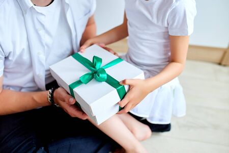 Unrecognizable daughter congratulating dad and giving present on birthday at home, little girl is giving her handsome father a gift box on Father's day. I love you, dad. Happy Father's Day.の写真素材