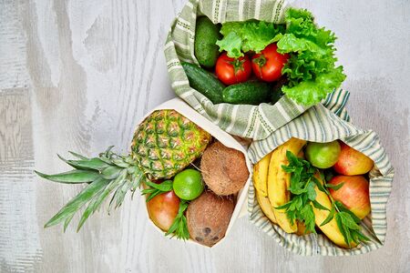 Flat lay of eco friendly grocery shopping cotton bags with organic fruits and vegetable on white background. Zero waste, plastic free lifestyle concept. Healthy veggie food diet and detox.の写真素材