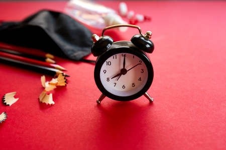 Time to Back to school in a new reality, flat lay schooling after the pandemic, School supplies, protective mask and antiseptic on a red background, space for text.の写真素材