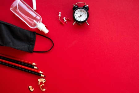 Time to Back to school in a new reality, flat lay schooling after the pandemic, School supplies, protective mask and antiseptic on a red background, space for text.の写真素材
