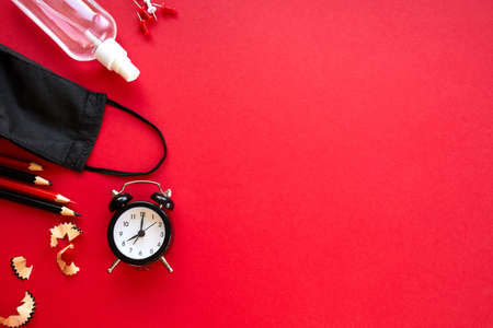 Time to Back to school in a new reality, flat lay schooling after the pandemic, School supplies, protective mask and antiseptic on a red background, space for text.の写真素材