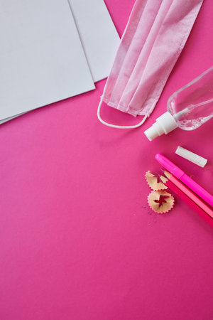 Flat lay schooling after the pandemic, Back to school in a new reality, School supplies, protective mask and antiseptic on a pink background, space for text.の写真素材