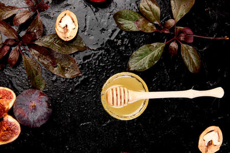 Autumn frame background. Autumn food still life with season fruits grape and figs, honey on a black...