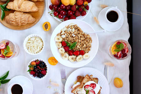 Fresh and bright continental breakfast table, abundance healthy meal variety crunch cereal, french toast, fruits, lemonade, coffee, croissant on table served, top view, flat lay, copy space, frame.の写真素材