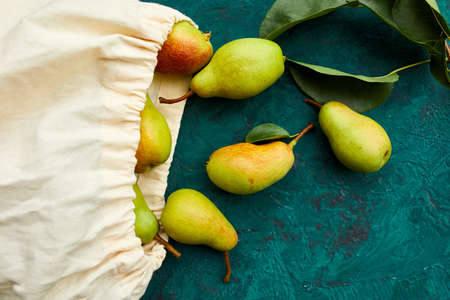 Fresh ripe fruits pears in string reusable shopping eco bag on a green background, grocery concept,...
