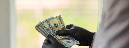 Man holding money dollars in hand in black medical gloves. Save money.