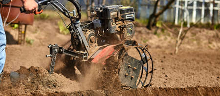 Man working in the garden with Garden Tiller. Garden tiller to work, close up. Man with tractor...